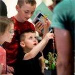 Kellen Mourer, 4, inspects a plant while exploring student projects with his family during the Groundswell Stewardship Initiative student project showcase on the Pew Grand Rapids Campus May 15.